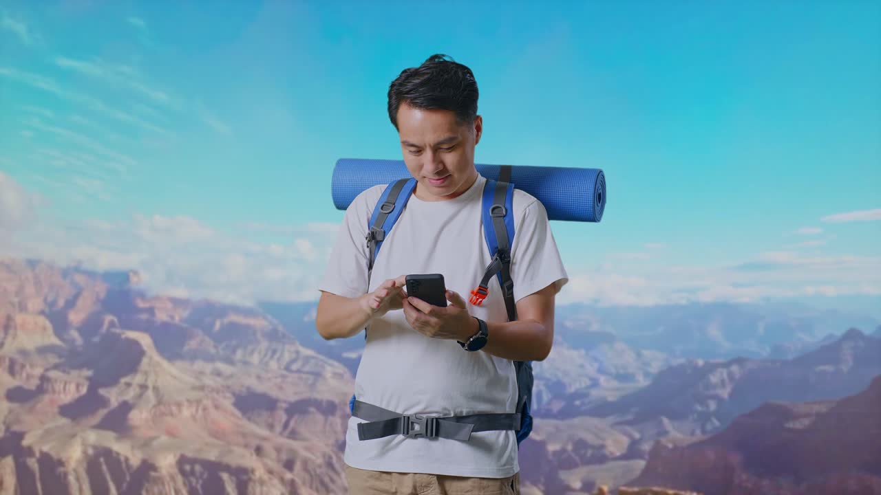 Asian Male Hiker With Mountaineering Backpack Enjoy Using Smartphone While Traveling At The Top Of Mountain