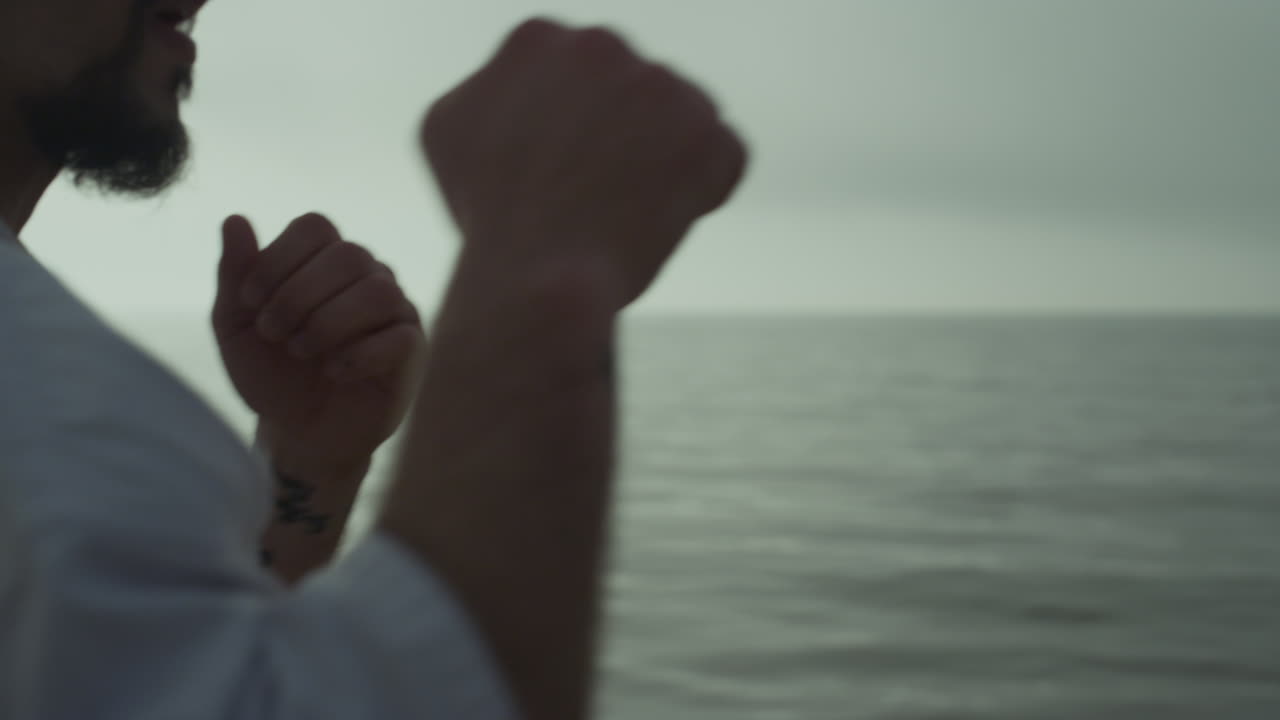 해가 뜨는 해변에 서서 싸우는 기술을 연습하는 남자