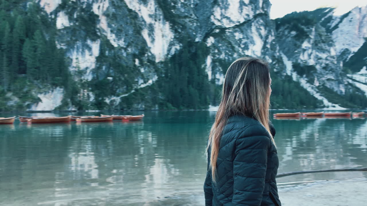 Tourist enjoying breathtaking view of Lago di Braies and surrounding mountains in Italy