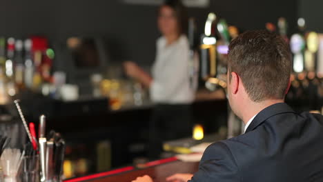 businessman ordering whiskey in a classy bar