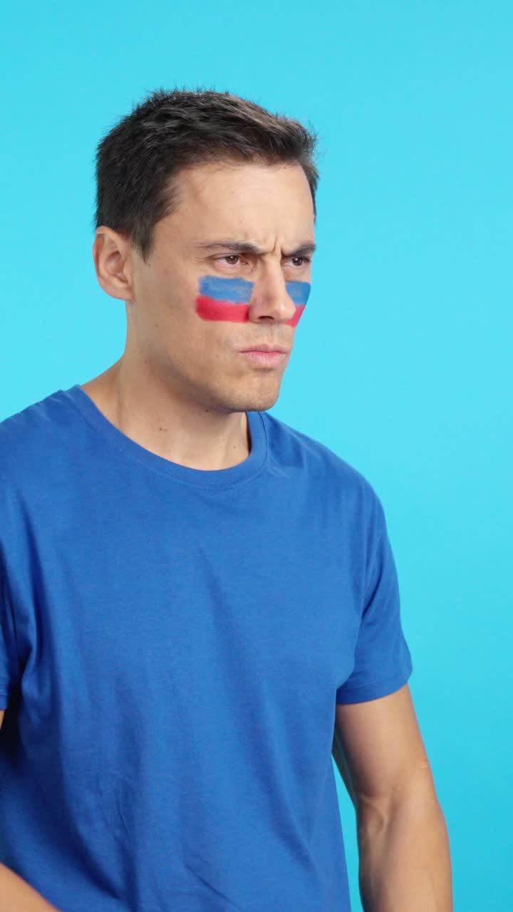 Man with haitian flag painted looking away with serious expression