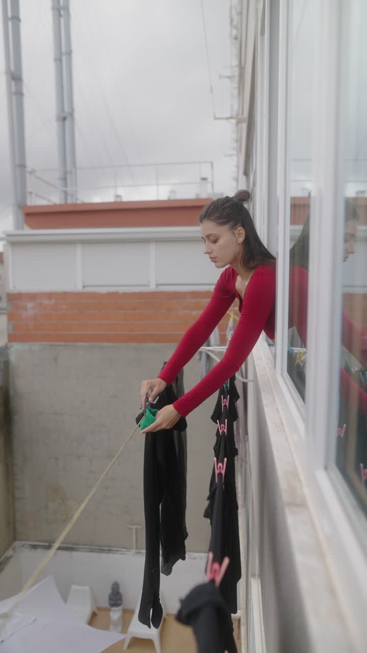 Woman Drying Clothes on Balcony
