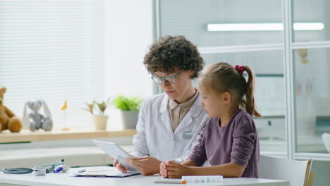 female doctor using tablet and talking with girl