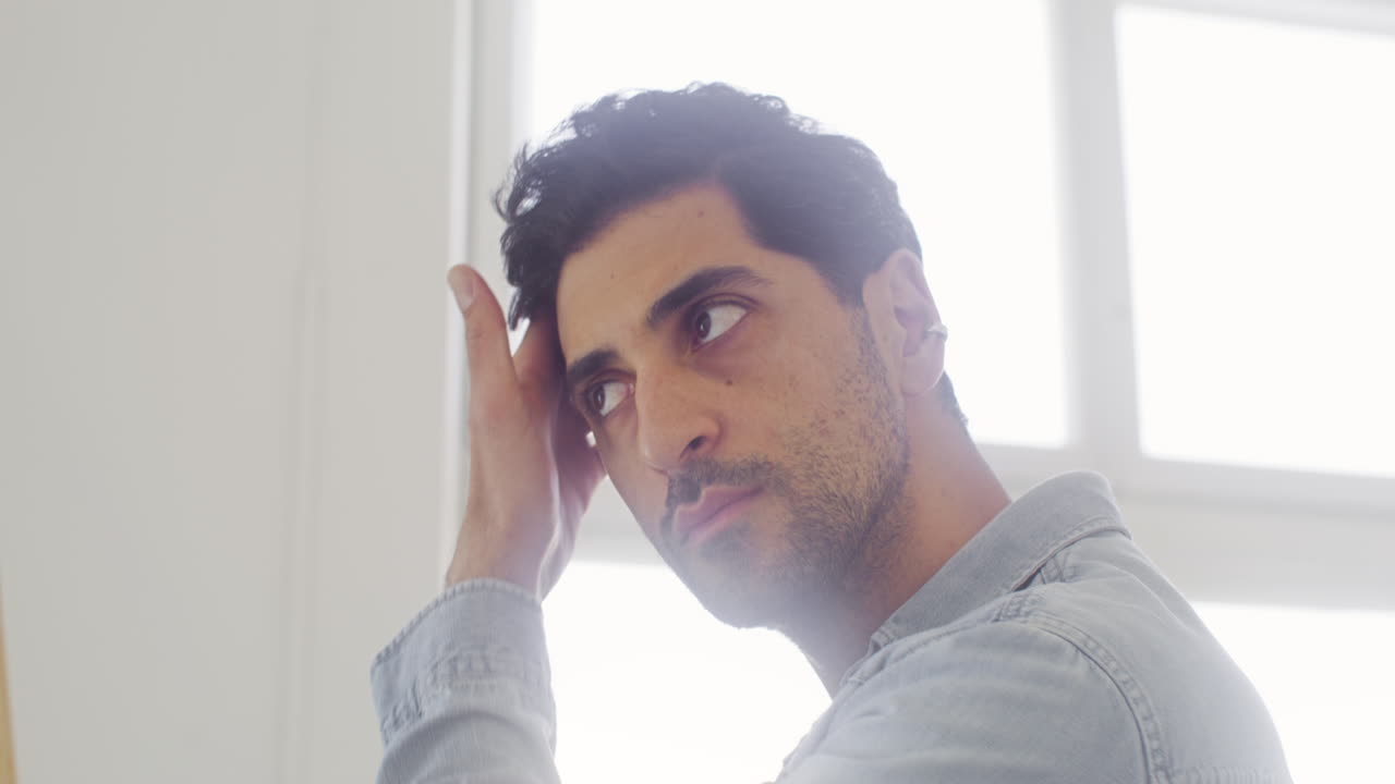 잘 손질된 남자가 거울을 보며 머리, 눈썹, 수염을 확인한다