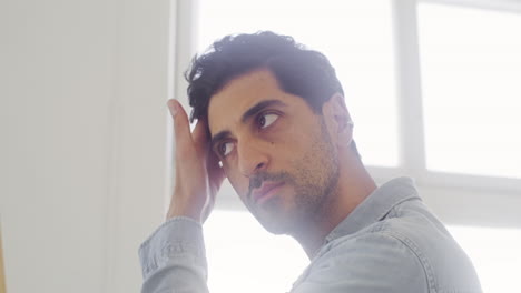 hombre bien arreglado revisando su cabello, cejas y barba en el espejo