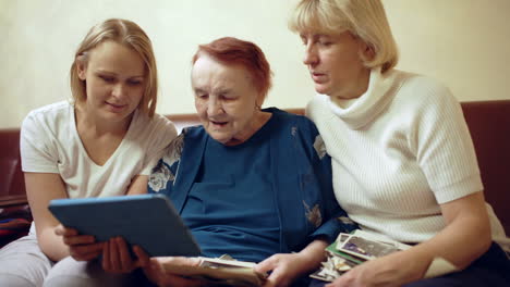 Dreiköpfige-Frauenfamilie-Schaut-Sich-Fotos-Auf-Dem-Touchpad-An