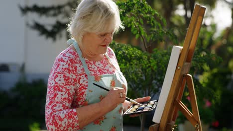 senior woman painting on canvas in the garden 4k