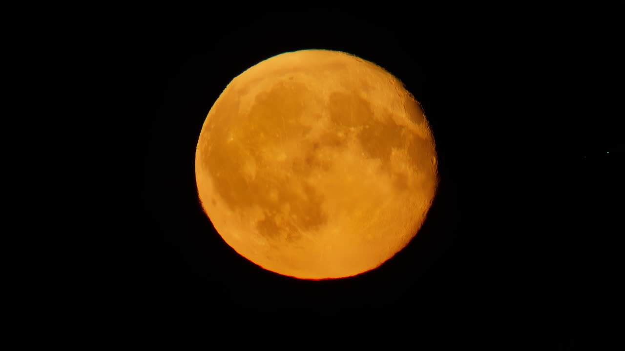Orange full moon illuminating the dark night sky with airplane passing. Slow motion