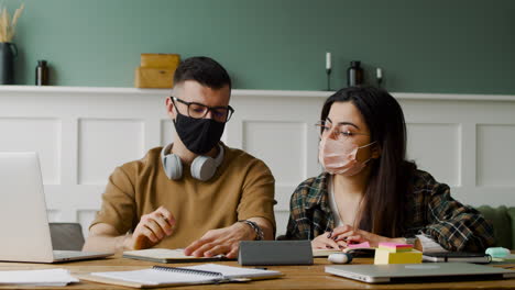 estudiante con auriculares hablando con una compañera en la mesa discutiendo sobre un proyecto usando una laptop