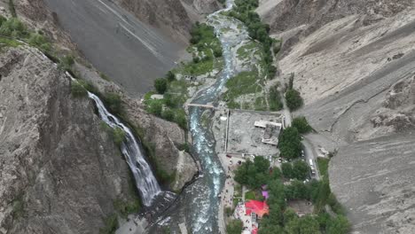 circular drone flying over mantoka waterfall in pakistan in skardu looking over waterfall and people and lake in beautiful landscape