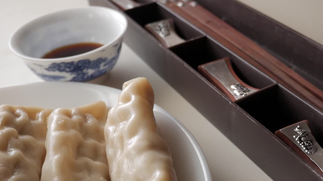 Fresh dumplings on a plate with soy sauce and chopsticks in soft morning light