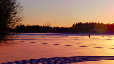 Person-is-skiing-cross-country-in-far-distance-shot-during-sunset