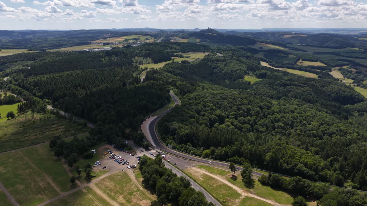Car racing circuit in the German Eifel region, specifically the Nurburgring near Nurburg, captured in aerial video