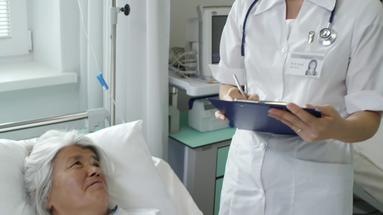 un médico asiático hablando con un paciente anciano.