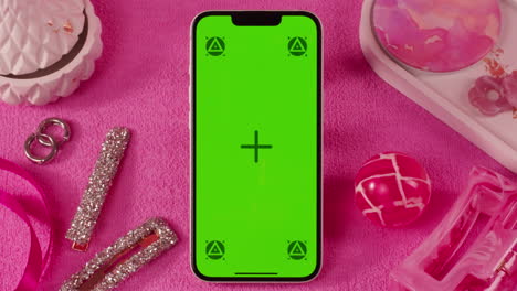 pink aesthetic flat lay with green screen phone
