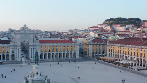 Aufsteigende-Luftaufnahme-Von-Menschen-Auf-Dem-öffentlichen-Platz-Praca-Do-Comercio-In-Lissabon-Mit-Arco-Da-Rua-Augusta-Und-Wohnhäusern-Im-Hintergrund