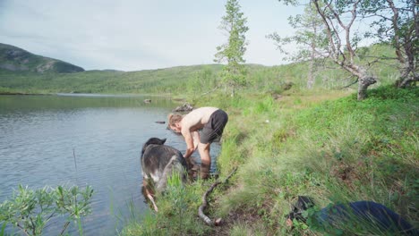 man and dog took a break by cleaning up on the lake in ånderdalen national park in the island of senja, norway