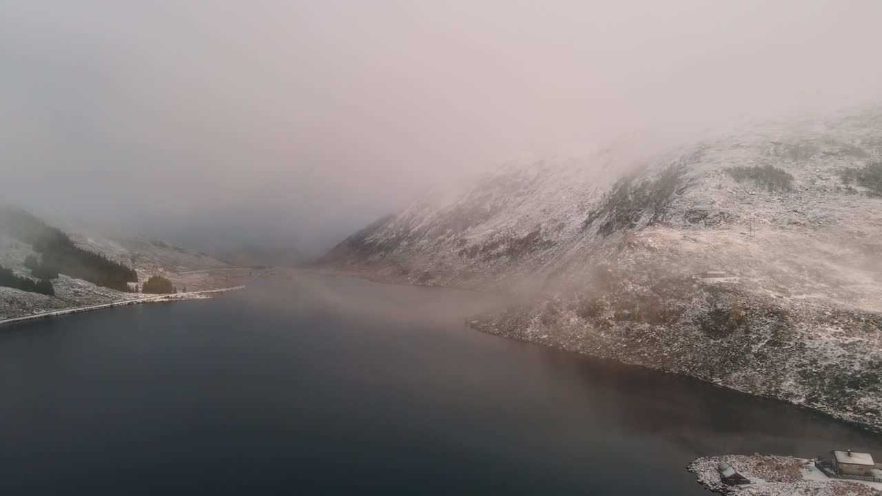 Lake with mountains surrounding it with foggy weather