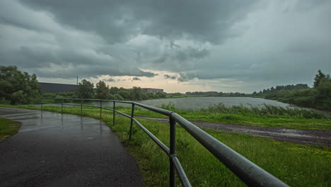 cloudy sky over calm lake and empty rural road on a rainy weather