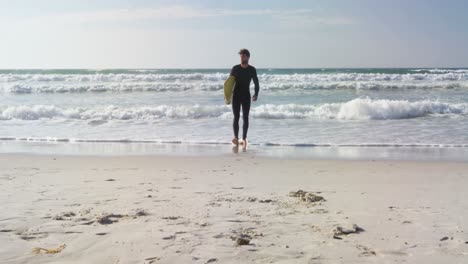 male surfer walking with surfboard at beach 4k