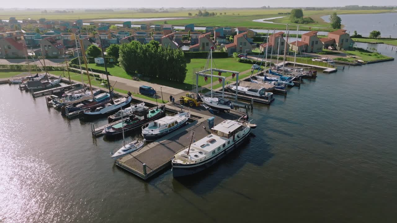 Drone performing semi orbit showing boats moored next to houses and green open space