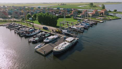 drone performing semi orbit showing boats moored next to houses and green open space