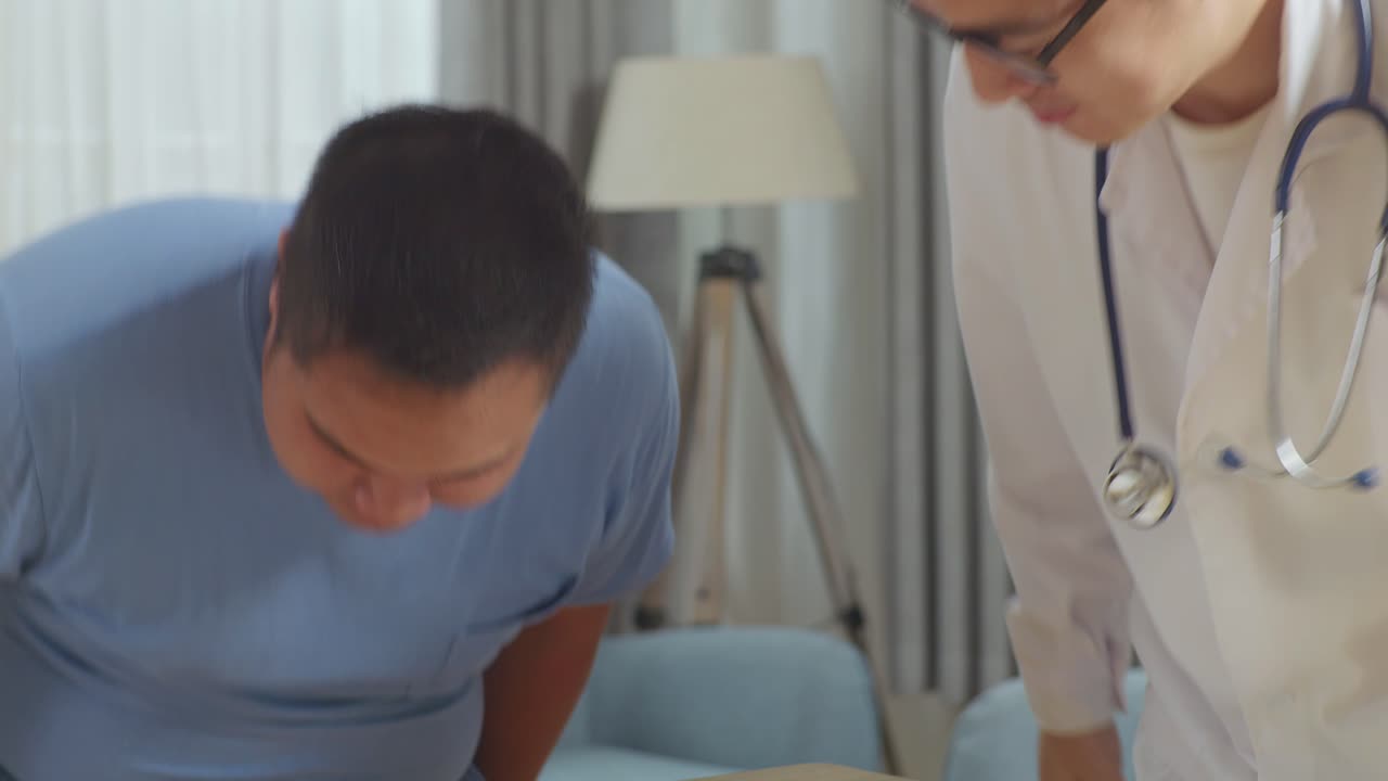 아시아 남성 의사가 클리닉에서 한 남성 환자를 만나고, 클리닉에 들어가서 손을 흔들고, 앉아서 의료 검사에 대해 논의합니다.