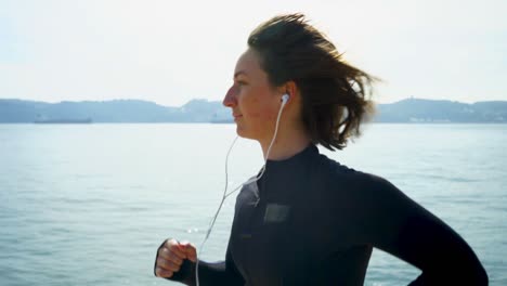 Smiling-young-woman-running-at-riverside