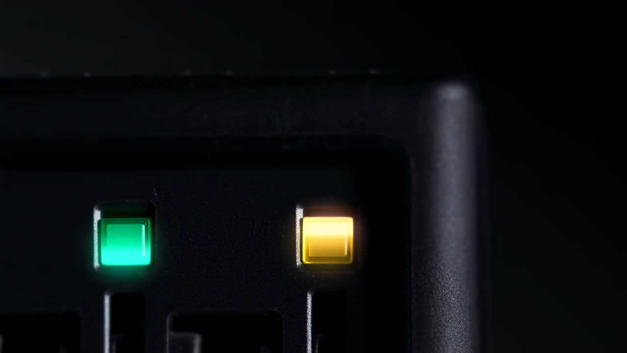 Close-up of a dark electronic control panel with two illuminated status indicators, one green and one amber, set against a minimal black background with a