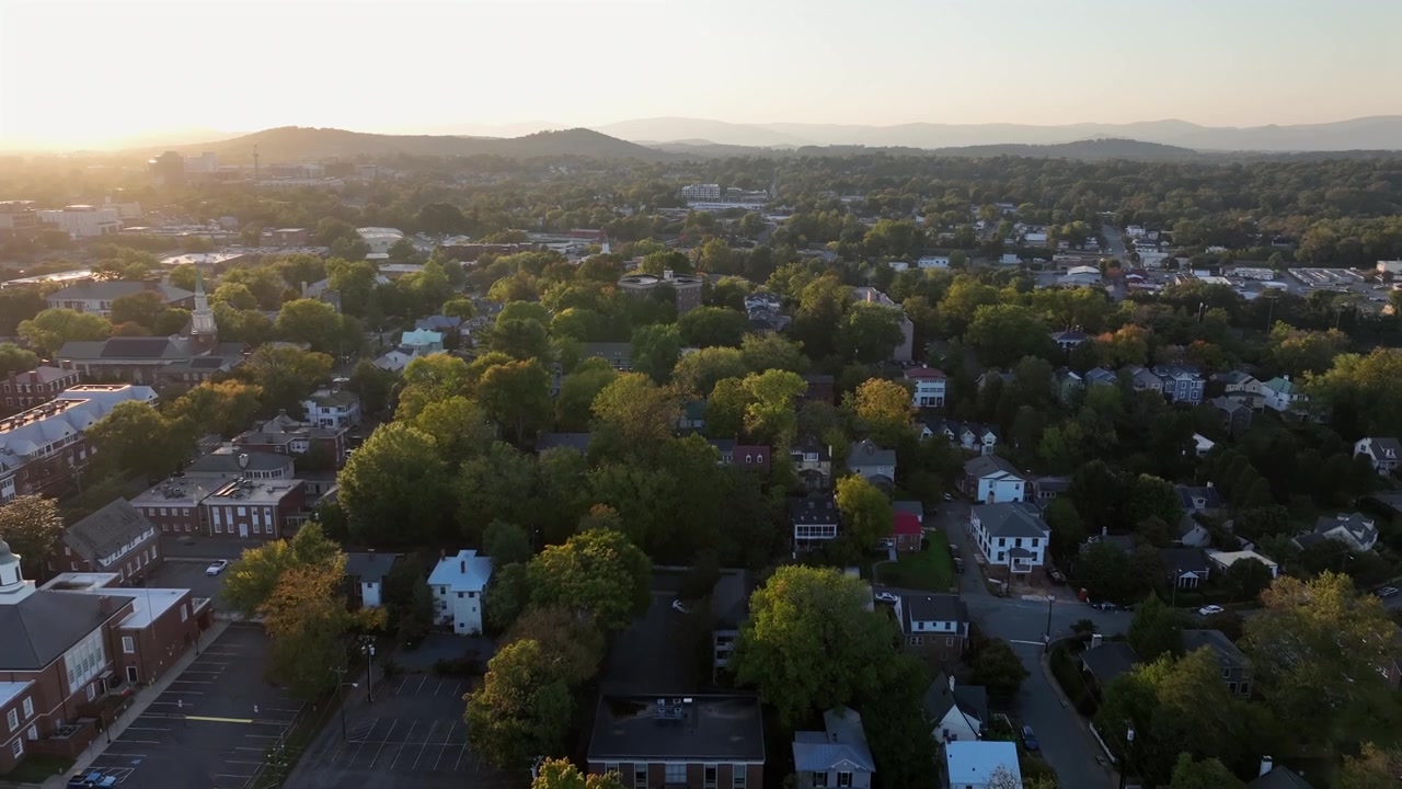 Aerial establishing shot over quaint neighborhood of america at sunset. Housing area with homes and buildings in USA. Panorama wide shot.