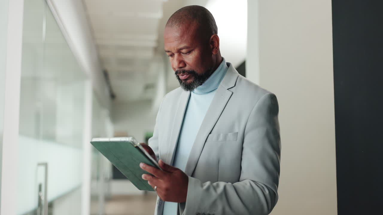 Focused Businessman Using Digital Tablet in Modern Office Hallway