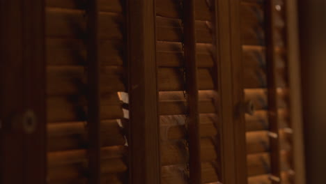 a man opens wooden shutters, showing indifference to smoke and fire outside