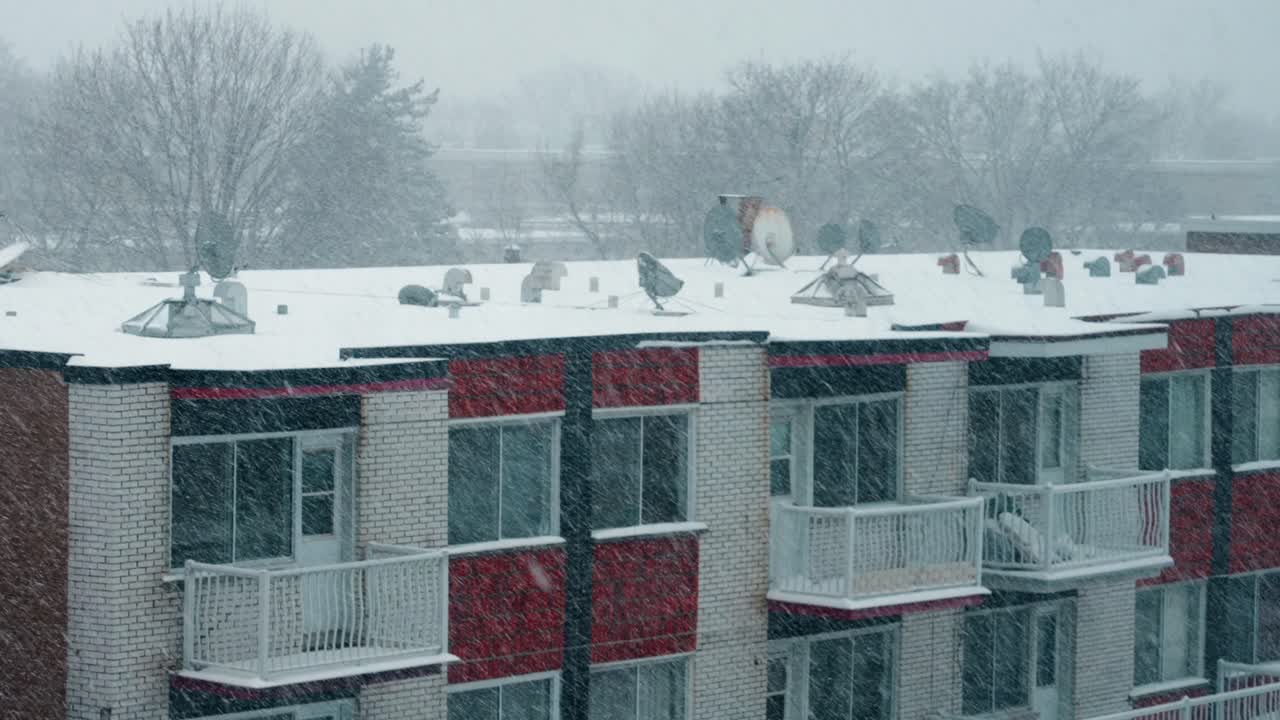 fuertes nevadas invernales sobre el techo de un edificio residencial de ladrillos con chimeneas 4k