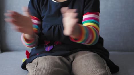 a young girl clapping her hands while sitting on a couch