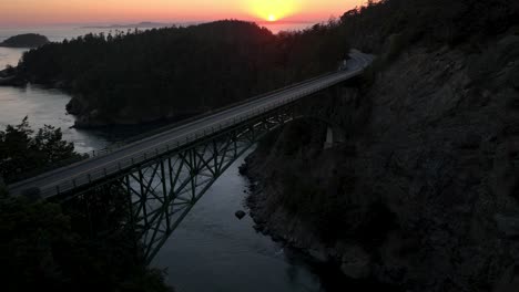 aerial shot flying over the shorter side of the deception pass bridge at sunset