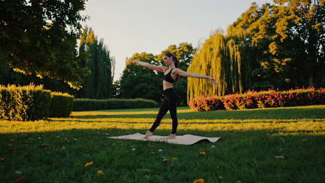 woman practicing yoga in a park at sunset