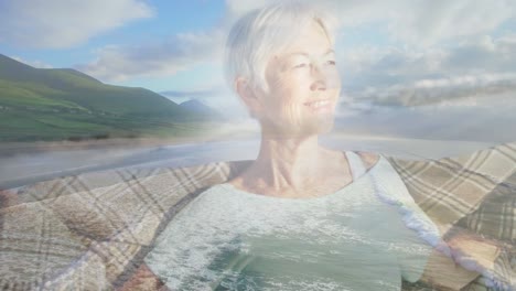 animation of glowing light over smiling senior woman by seaside