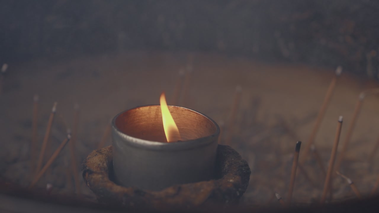 Lit candle surrounded by burning incense sticks at Buddhist temple shrine Japan