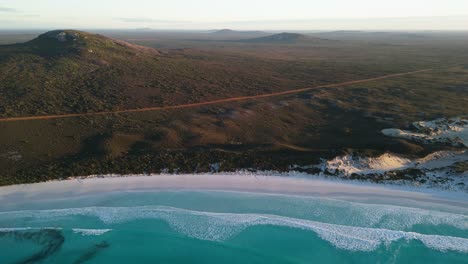 surf at sunrise with mountains of cape le grand in the background