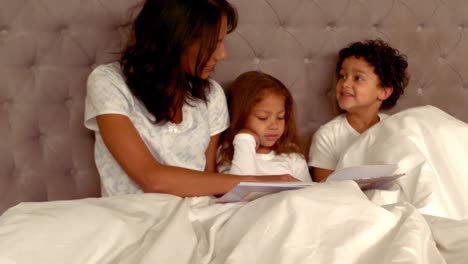 sonriente madre hispana con sus hijos en la cama