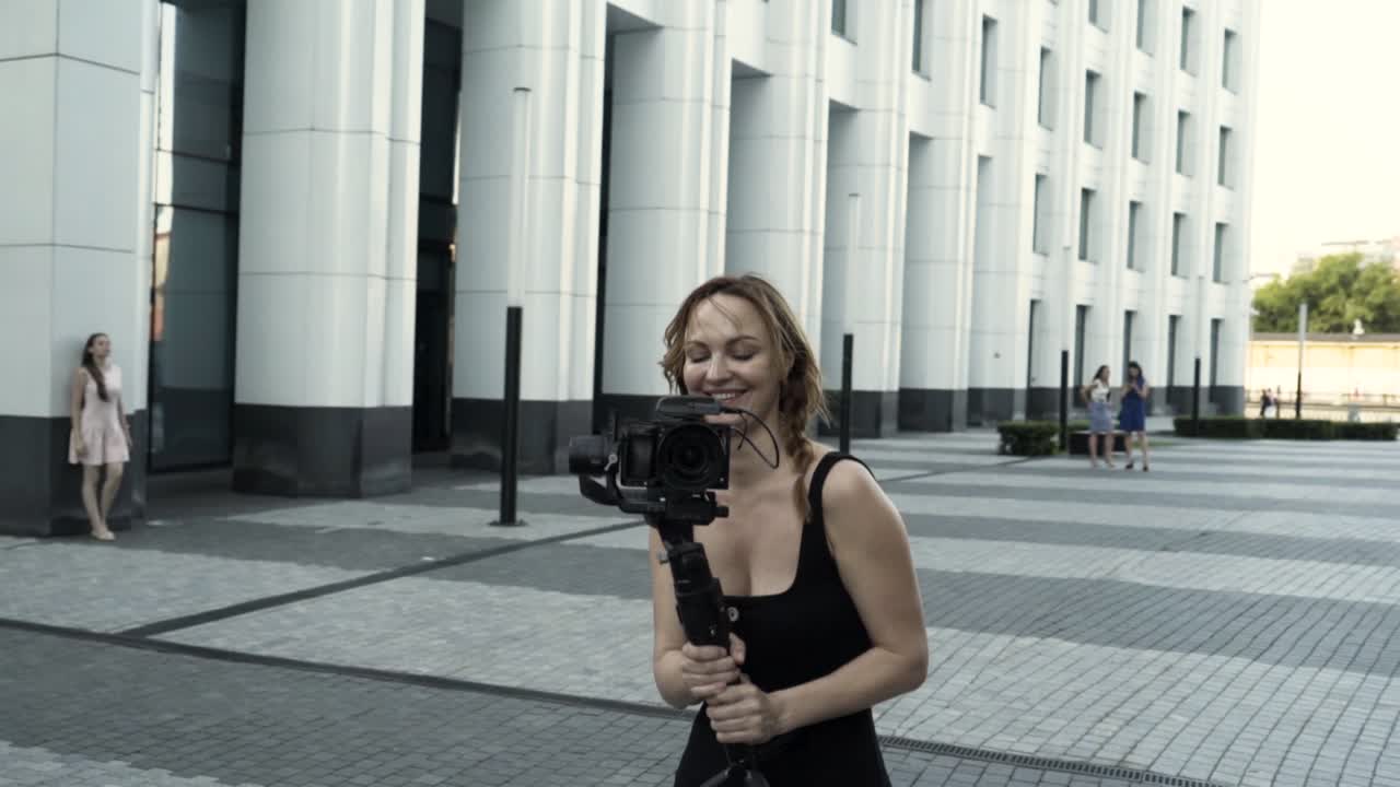 mujer filmando en gimbal en la ciudad