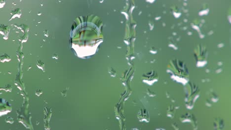 captivating water droplets gracefully adorn a window, creating an ethereal illusion with reflections of vibrant greenery behind, evoking serenity and calmness