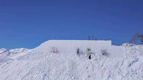 people using heavy equipment to shape a snow