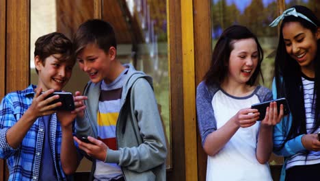 Group-of-school-friends-using-mobile-phone-outside-school