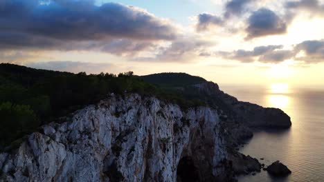 Ibiza-sunset-overlooking-a-rocky-sea-cliff-and-calm-ocean