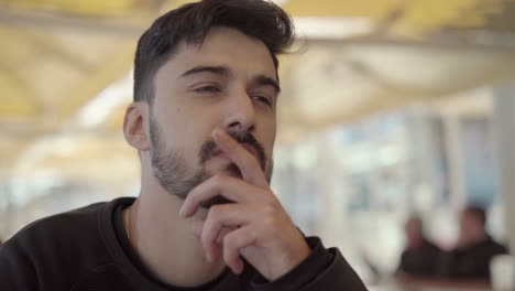 thoughtful young man holding hand on chin and looking away