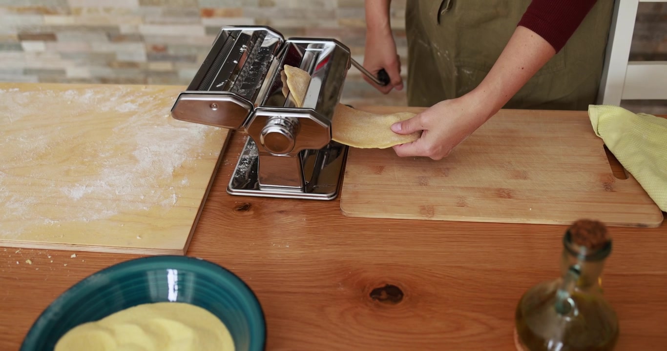 Person Using Manual Pasta Machine to Roll Dough