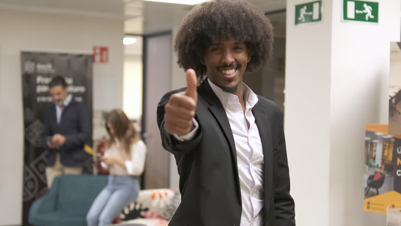 Happy confident creative businessman standing with thumbs up in office