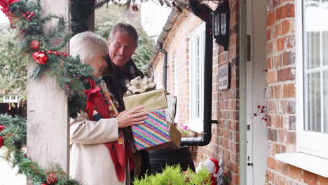 grandparents being greeted by family as they arrive for visit on christmas day with gifts