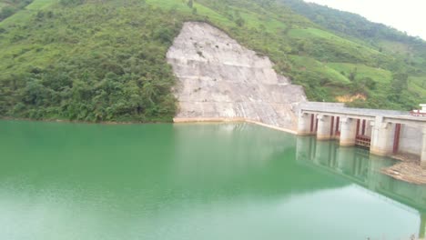 A-hydro-electric-dam-sits-in-a-valley-creating-a-bluish-green-lake-in-the-mountains-of-northern-Vietnam